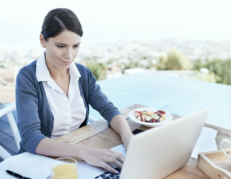 A woman working by the pool with her laptop.