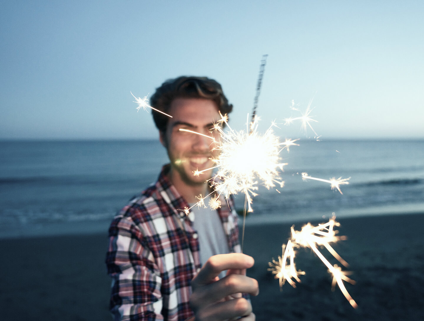 Strahlender Mann mit einer Silvesterkerze in der Hand