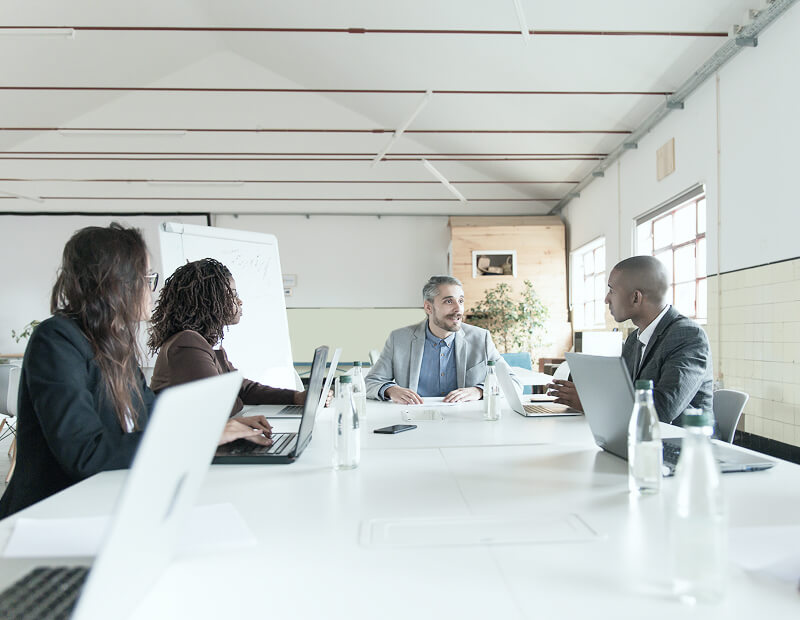 Several people sit at a large table and hold a meeting